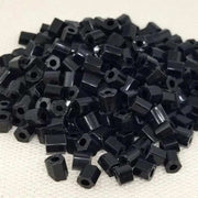 20 grams of 4mm black polygon tube glass beads scattered.